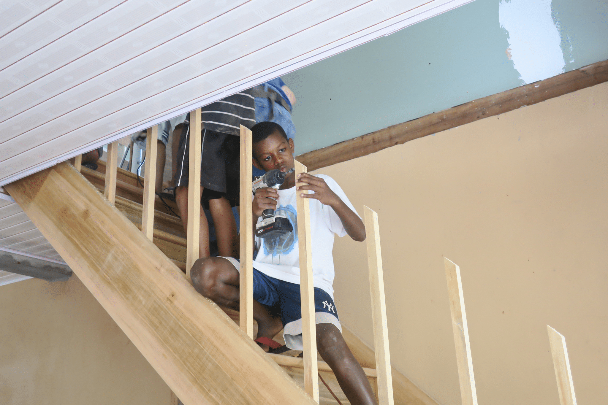 Boy on the stairs drilling on the wood