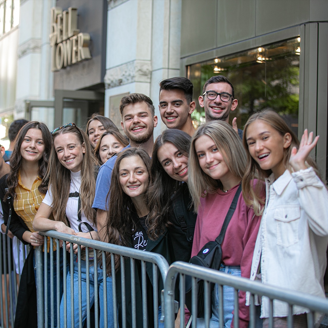 group of attendees waiting in line smiling and waving