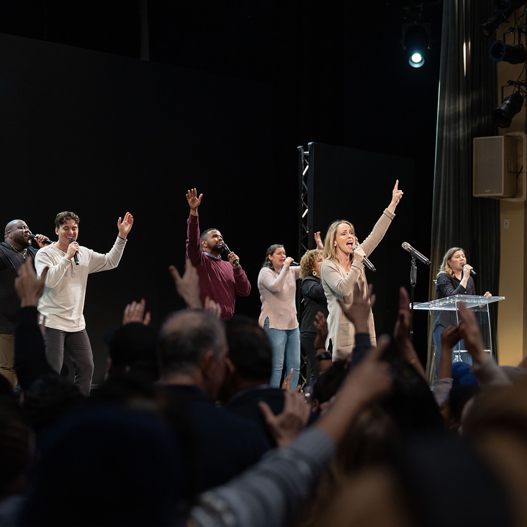 Worship at altar call with singers with lifted hands and Sue Pettrey singing and congregation having hands lifted