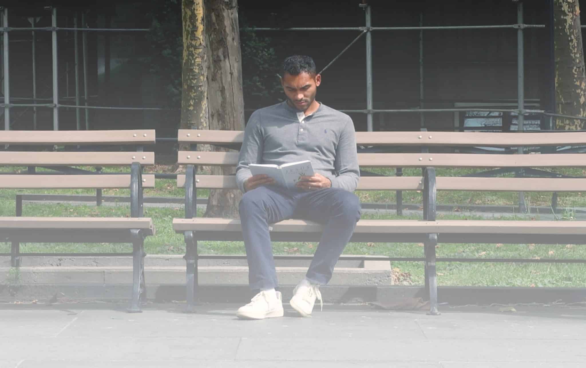 Man sitting on NYC park bench with devotional book