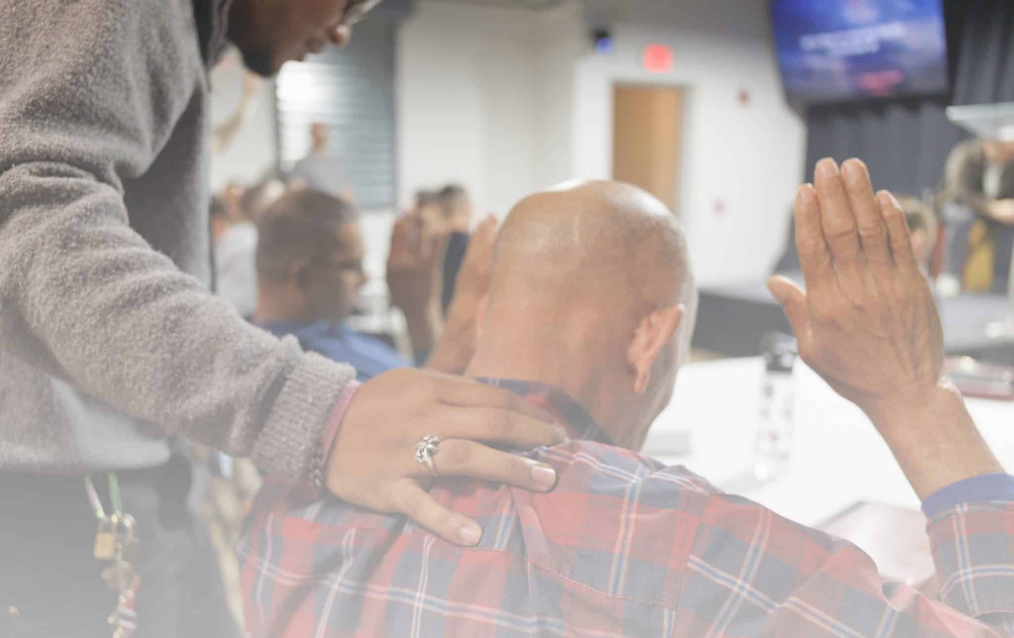 A brother places his hands on another brother in prayer.