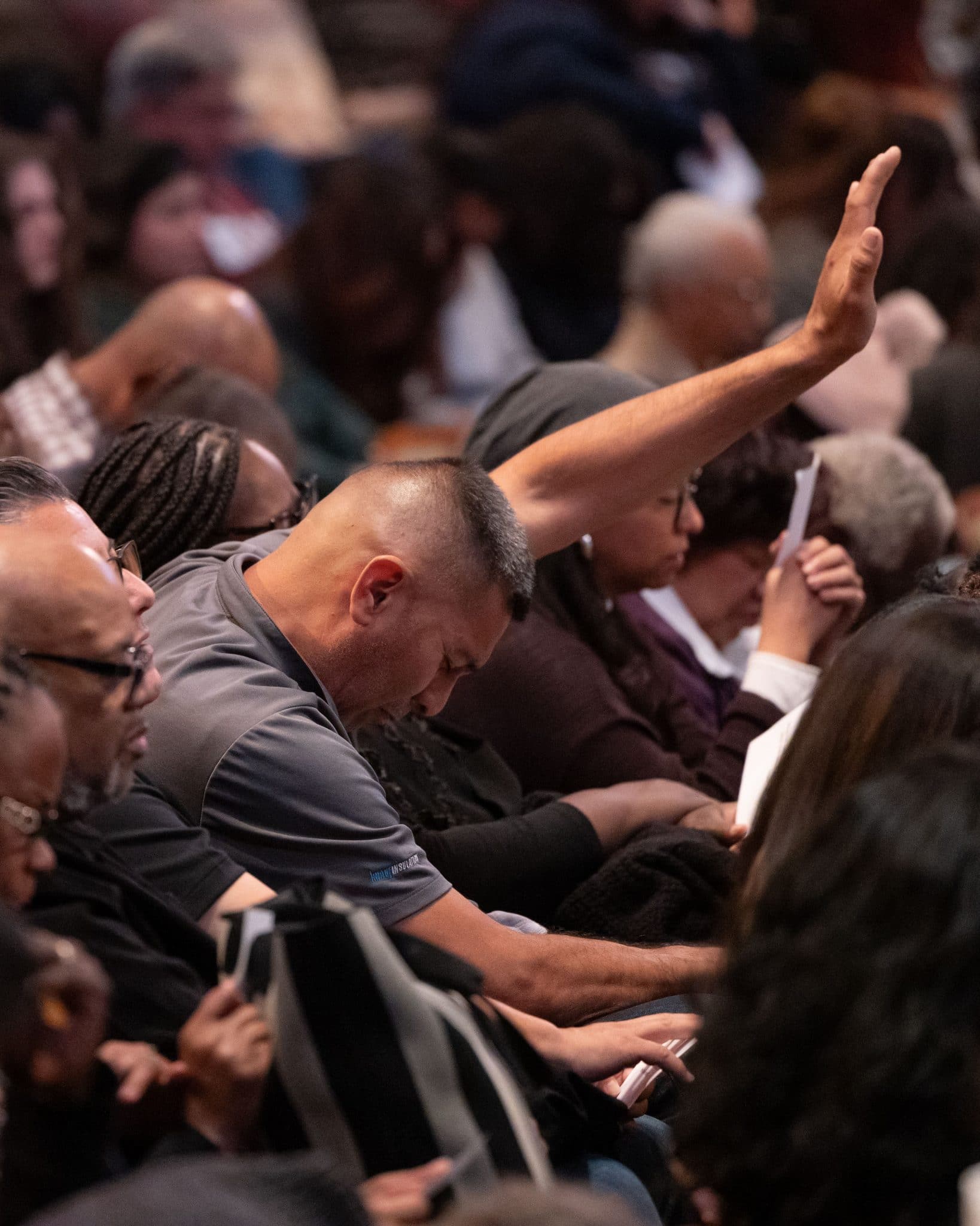 A man lifting his hand in prayer in the congregation