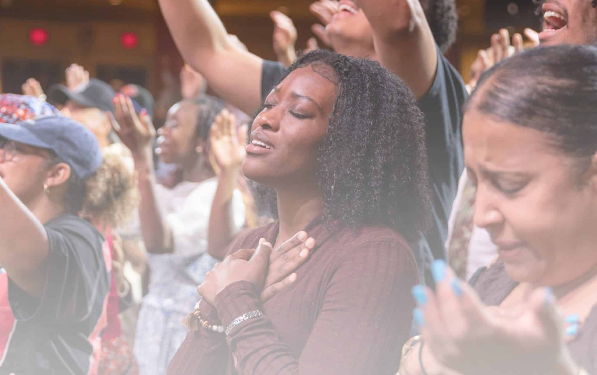 A woman with her eyes closed and hands together in prayer, trusting that God has a plan.