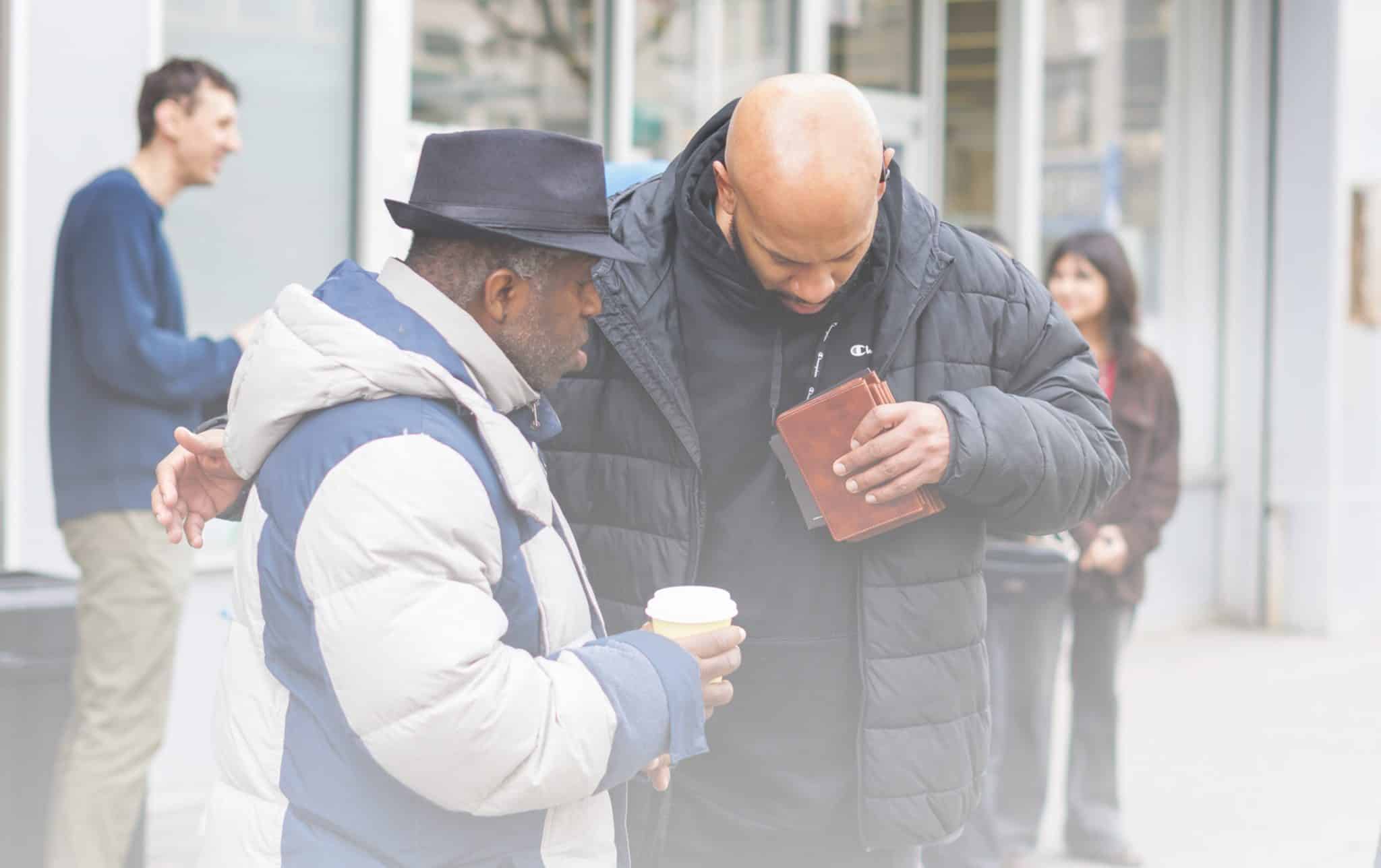 Two people praying together on a New York City street.